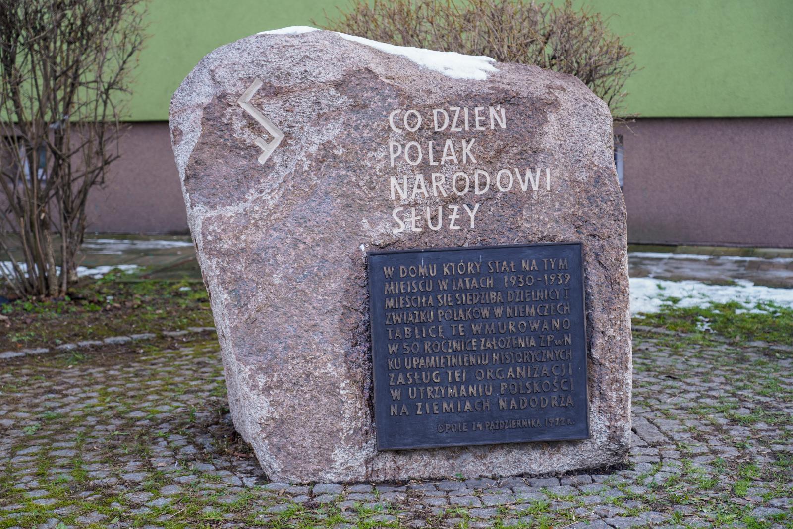 głaz z tablicą pamiątkową usytuowany na rogu ul. Książąt Opolskich i Sądowej (w miejscu nieistniejącego Domu Polskiego) w 1972 r. z okazji jubileuszu 50.lecia powstania Związku Polaków w Niemczech. Na głazie wyryto znak Rodła oraz jedną z pięciu Prawd Polaków. Fot. Witold Chojnacki