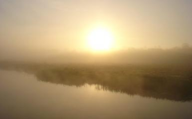unosząca się nad rzeką mgła oraz promienie słoneczne przebijające się przez nią