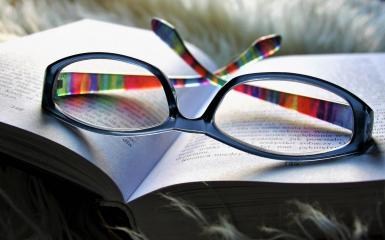 Otwarta książka, na niej położone okulary