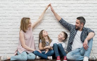 Rodzice z dwójką dzieci siedzący przy ścianie