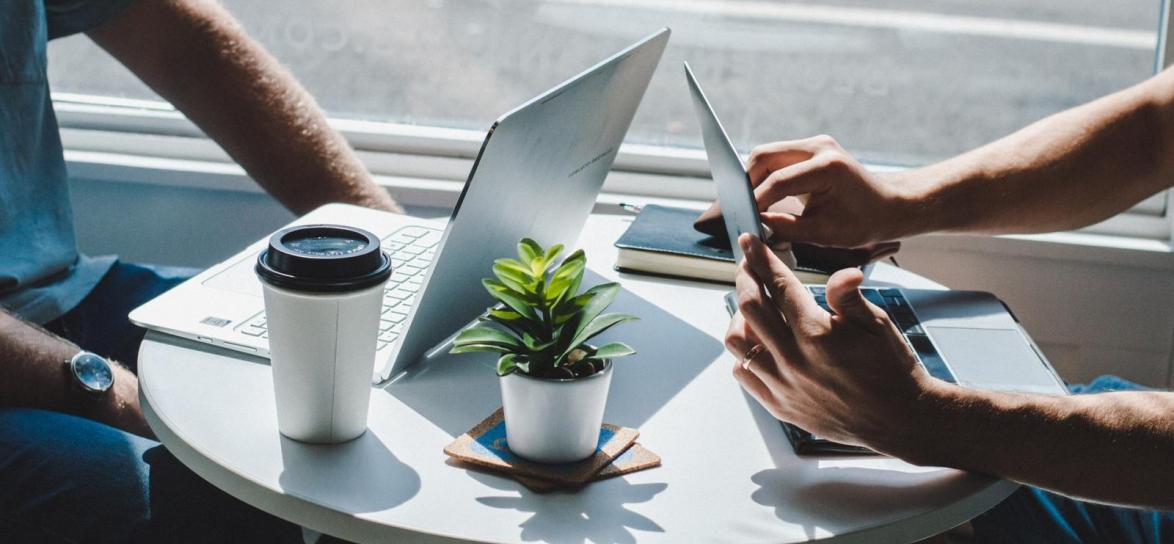 Dwie osoby siedzące przy stole obok laptop