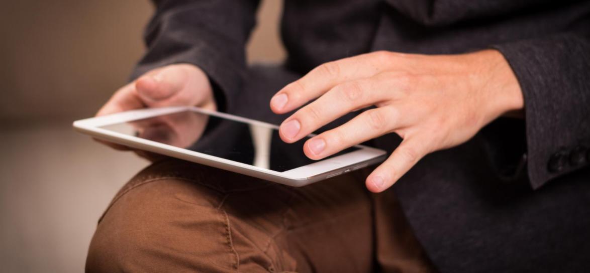 Osoba trzymająca tablet w dłoni 