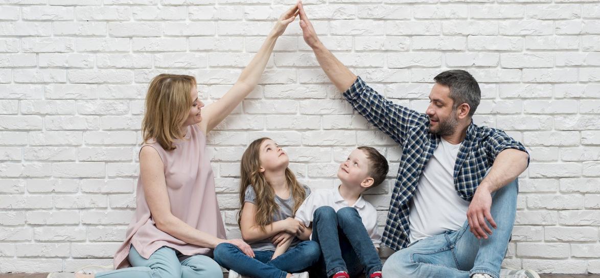 Rodzice z dwójką dzieci siedzący przy ścianie